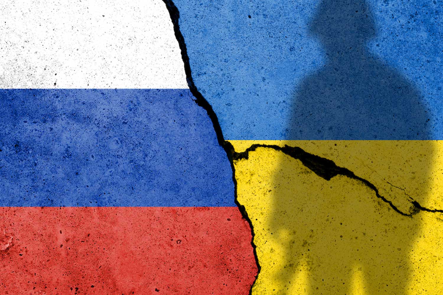 An image of the Russian flag and Ukrainian flags spliced together, cracking in the middle. A shadow of a soldier covers the Ukranian flag.