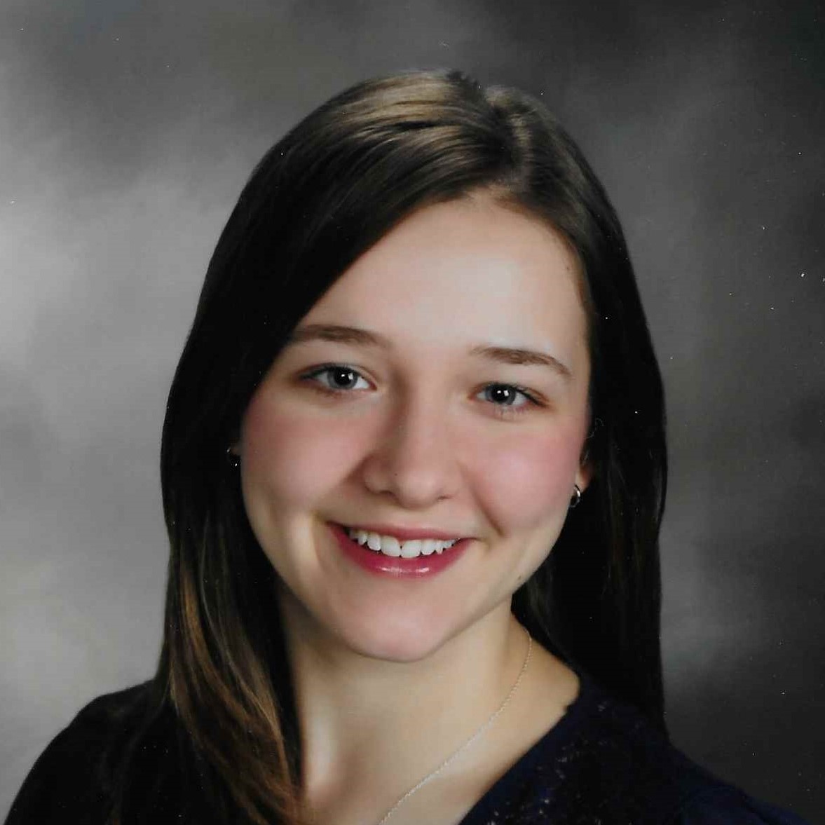 Emma Calkin's headshot. A person with long, dark hair and side bangs smiles at the camera.