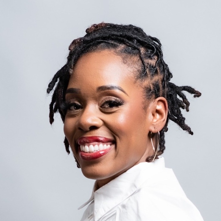 Shijuade Kadree's headshot. A person wearing a collared shirt and red lipstick smiles at the camera.