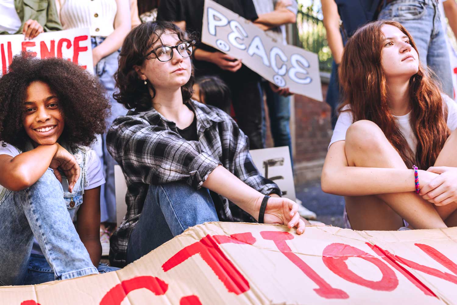 A photo of young people at a protest holding a sign reading "Action"